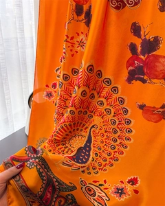 Detailaufnahme des orangefarbenen Seidenschals mit Pfauenmuster und Granatapfel-Print