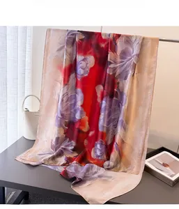 Detail of floral printed satin scarf featuring large purple blooms and gradient red silk texture