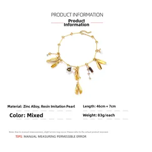 Detail of elegant leaf and flower charms with imitation pearls on a gold chain necklace