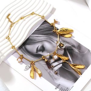 Detail of luxury necklace with alloy leaves, pearls and feather pendants on magazine