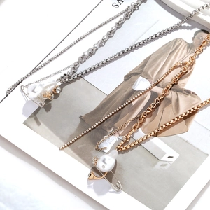 Détails de colliers superposés or et argent avec perles baroques et épingles en strass