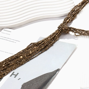 Close-up of multi-strand beaded tassel necklace with metallic bronze glass tubes and knots