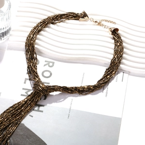 Multilayer beaded collar necklace with fringe knot design on a wavy display