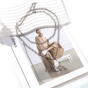 Collier superposé avec perle irrégulière et pendentif saturne sur plateau blanc