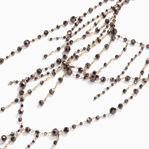 Détails macro du collier multi-rangs avec perles grises facettées et maillons dorés