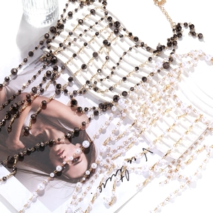 Détail d'un collier multi-rangs doré avec perles blanches et perles facettées