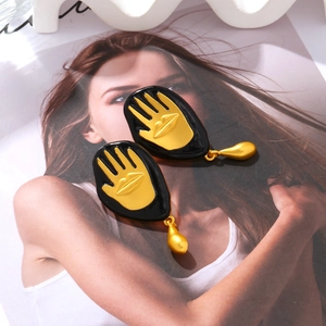Detail of vintage hand and lip drop earrings with gold and black enamel finish