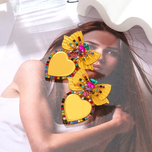 Orecchini a cuore vintage con cristalli colorati e fiocco d'oro su rivista di moda