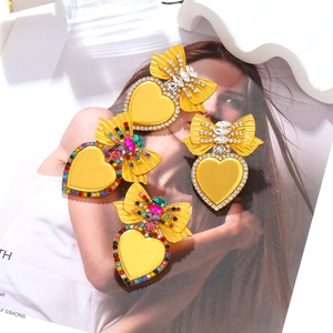 Dettaglio di orecchini vintage a cuore e fiocco con strass colorati su metallo dorato
