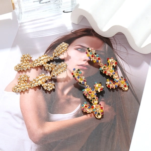 Detailed view of long wavy gold-plated earrings with white and colorful rhinestones