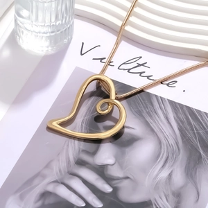 Minimalist gold hollow heart pendant necklace with sleek snake chain shown on a magazine