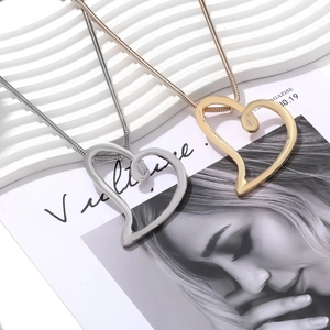 Close-up of gold and silver heart necklaces with sleek snake chains on a modern background