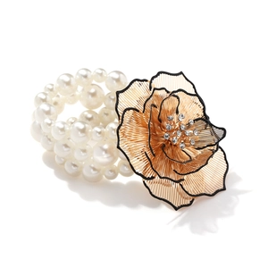 Detail of bohemian multilayer pearl bracelet with a large gold wire flower and rhinestones