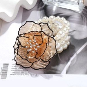 Detailed view of layered faux pearl bracelet featuring a large gold metal floral accent