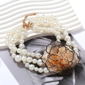 Collier de perles à trois rangs orné d'un grand pendentif fleur dorée avec cristaux