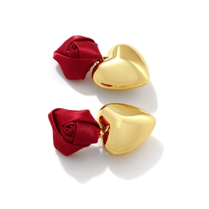 Close-up of handmade fabric red rose and polished golden heart drop earrings for women