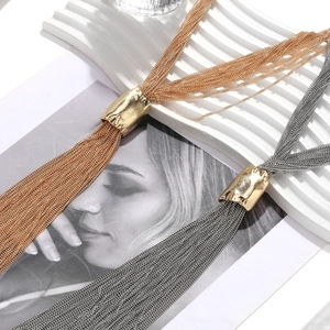 Detail of layered multi-strand gold and silver tassel chain necklace with textured metal slider