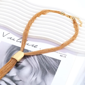 Detailed close-up of multi-layer gold chain necklace with flowing metal tassels