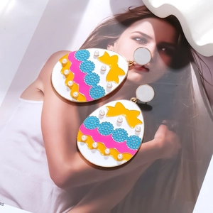 Colorful enamel Easter egg earrings with yellow bows and pearls on a white base