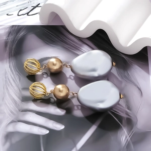 Detailed view of baroque drop earrings with gold hollow spheres and irregular grey pendants