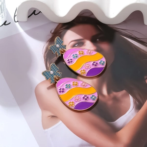 Macro detail of colorful Easter egg earrings with blue bow and white faux pearl