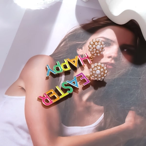 Close-up of Happy Easter earrings with colorful enamel letters and faux pearls