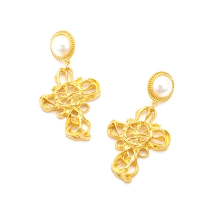 Détail de boucles d'oreilles baroques dorées avec croix filigrane et perles vintage