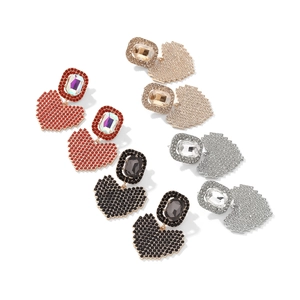 Détail de boucles d'oreilles pendantes en cœur pixelisé serties de strass brillants