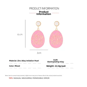 Detail view of pink Easter egg earrings with gold Happy Easter text and white pearl stud