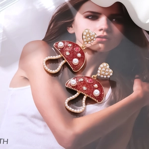 Detail of mushroom earrings with red enamel, pearls and heart studs on magazine cover