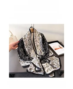 Close-up of silk scarf with gold paisley pattern and elegant black borders