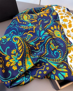 Detail of silk-like paisley scarf showing deep blue satin texture and floral border