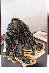 Detail of luxury paisley print silk shawl in black and gold with satin finish