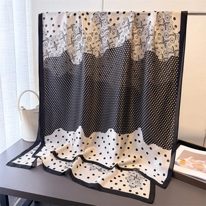Detail of black and white geometric silk scarf draped elegantly over a display stand
