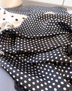 Close-up of black and white polka dot silk scarf showing smooth texture and soft drape