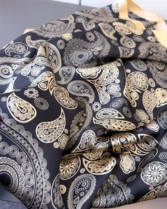 Macro detail of silky paisley satin scarf showing black and yellow printed fabric texture
