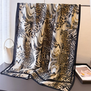 Detailed close-up of leopard print silk shawl featuring black contrast stitched edges