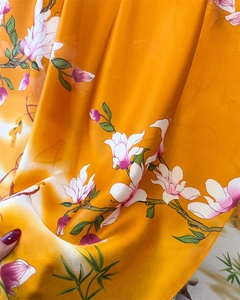 Close-up of silk scarf fabric showing vibrant orange magnolia print and soft texture