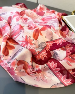 Detailaufnahme des Seidenschals mit Blumenmuster, roten Saumkanten und feiner Satinstruktur