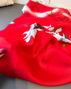 Macro shot of red floral silk scarf featuring satin luster and delicate leaf pattern