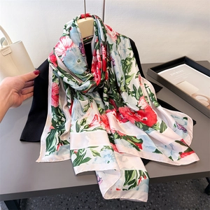 Elegant floral print silk scarf featuring vibrant red and blue blooms on a white background