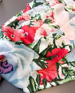 Detailed close-up of vibrant floral print silk scarf featuring red and blue blossoms