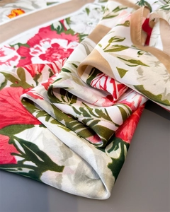 Detailed macro view of silky floral scarf with red blossoms and golden brown border