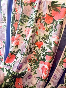 Close-up of lightweight floral satin fabric with coral and lavender blossoms and silk sheen