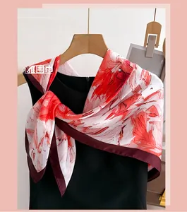 Détail d'un foulard en soie à imprimé floral, fleurs rouges et bordures rouge foncé