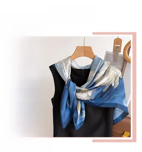 Détail d'un foulard en satin de soie à fleurs bleues drapé avec élégance sur un haut noir
