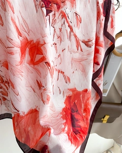 Détail d'un foulard en soie avec imprimé floral rouge et bordure marron foncé