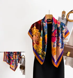 Detailed view of colorful floral silk scarf with orange blooms and dark purple borders