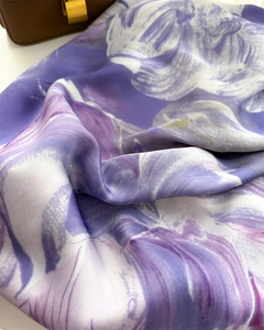 Detailed view of purple floral silk scarf showing smooth texture and draped fabric