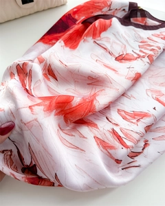 Détail d'un foulard en satin de soie avec motifs floraux orange vifs et texture élégante